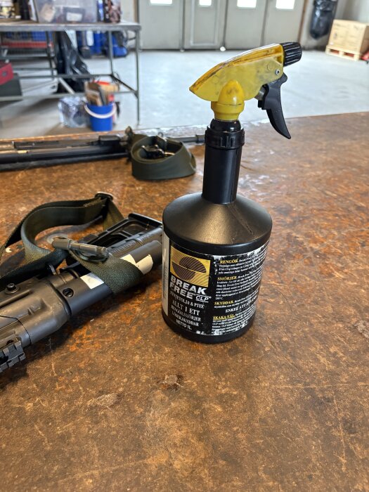 Flaska med rengöringsmedel Break Free CLP på ett bord, bredvid ligger ett gevär med grön rem.