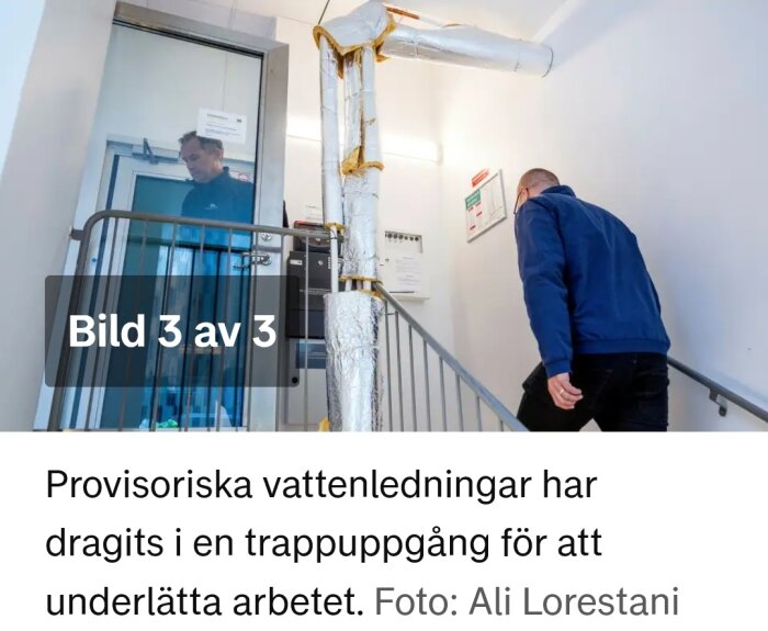 Provisoriska vattenledningar isolerade i trappuppgång, personer går i trappa.