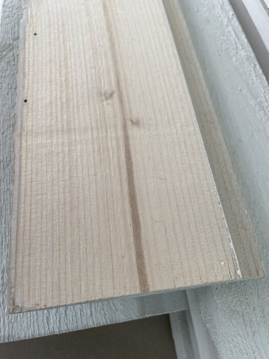 Träpanel i närbild, visar släta och obehandlade ytor på en mellnstruken ytterpanel med synliga träfibrer.