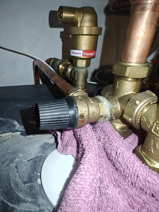 Ventilinstallation i kopparrör med Flamco Flexvent och en rosa trasa som ligger under anslutningen.