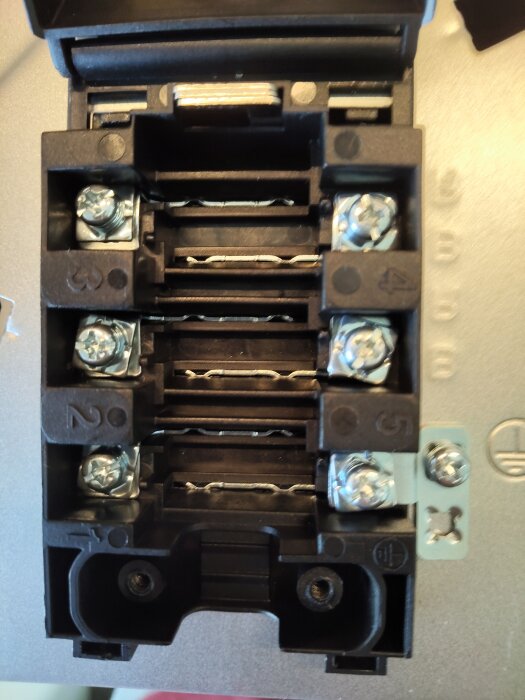 Närbild av en elektrisk terminal med numrerade skruvkontakter från 1 till 5, använd för att koppla termostaten till strömförsörjningen.