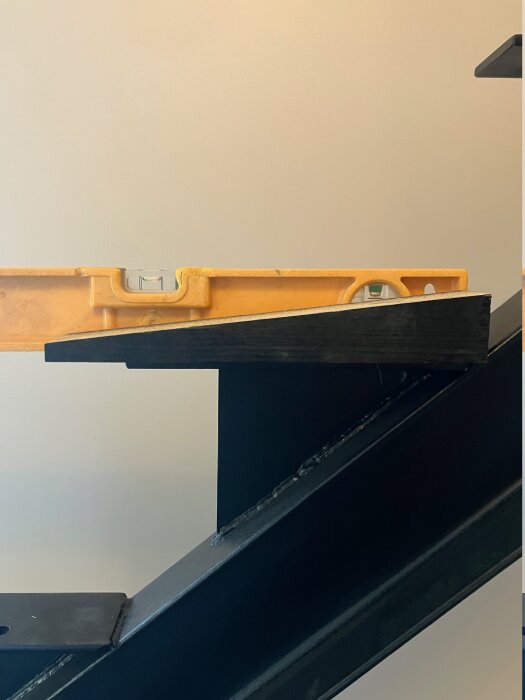 En monterad balktrappa med ett vattenpass placerat ovanpå ett trappsteg för att kontrollera lutningen i förhållande till balken.