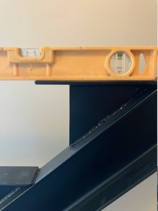 Vattenpass som mäter lutning på stålbalk, del av trappkonstruktion.