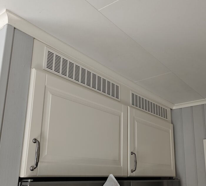 Överskåp med vit panel och ventilation i köket.