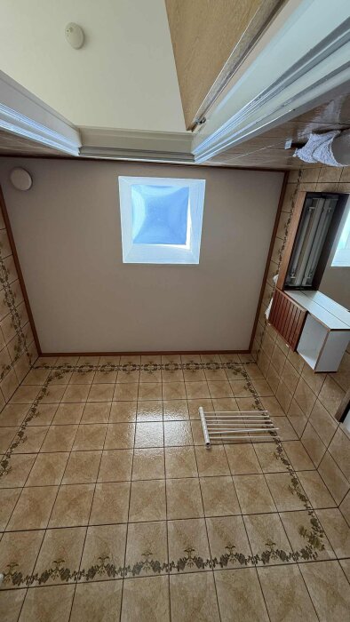 Badrum med beige och mönstrade klinkers, ett takfönster och en väggmonterad elementtork.