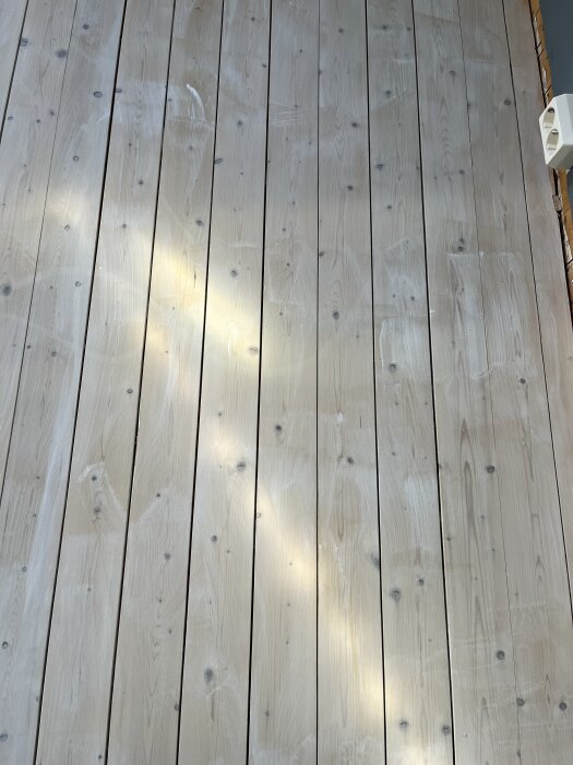 Slipat granundergolv behandlat med vitpigmenterad golvlut, med synliga ojämna och flammiga ytor.