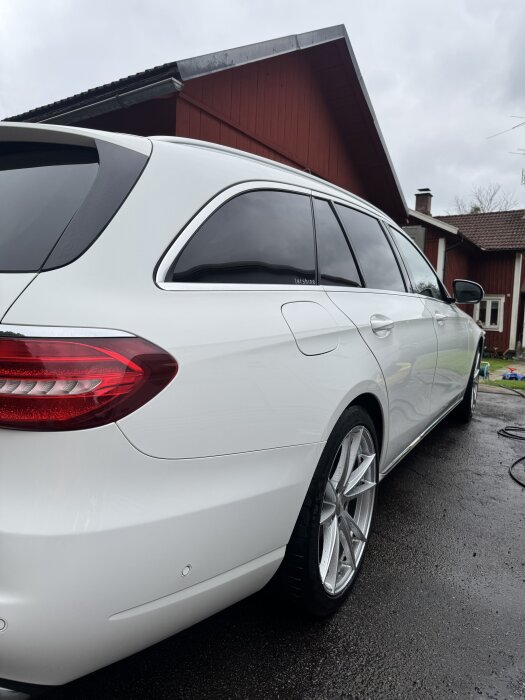 Vit bil från sidan med blanka fälgar och en röd byggnad i bakgrunden, testad med produkt Refract V 4.0 för lättare underhåll.