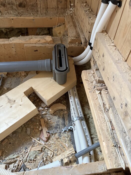 Bilden visar rördragningar och VVS-arbete i ett pågående badrumsrenoveringsprojekt med synliga trä- och plastmaterial.