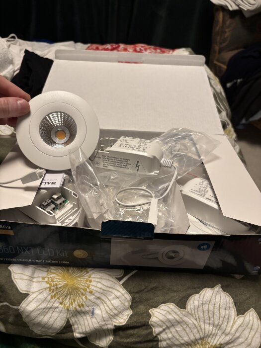 Förpackning med Malmbergs MD 360 NXT LED spotlights, innehållande spotlight-enheter och tillbehör i en öppen kartong.