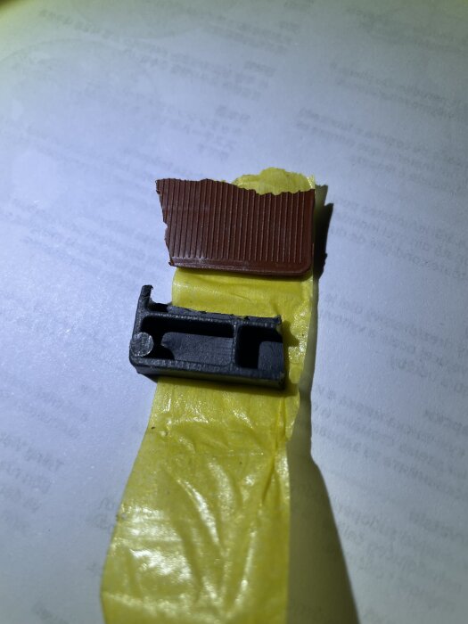 Hemgjorda mellanlägg, mörk plast och brun bit, på gul tejp, kritiserat diskho-montage.