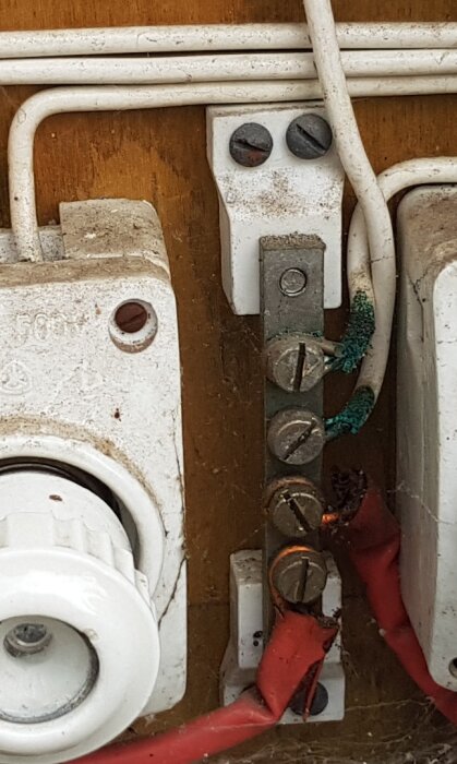 Elektrisk kopplingsplint med åldrande PVC-isolering, delvis avskalad isolering och oxiderade skruvar.