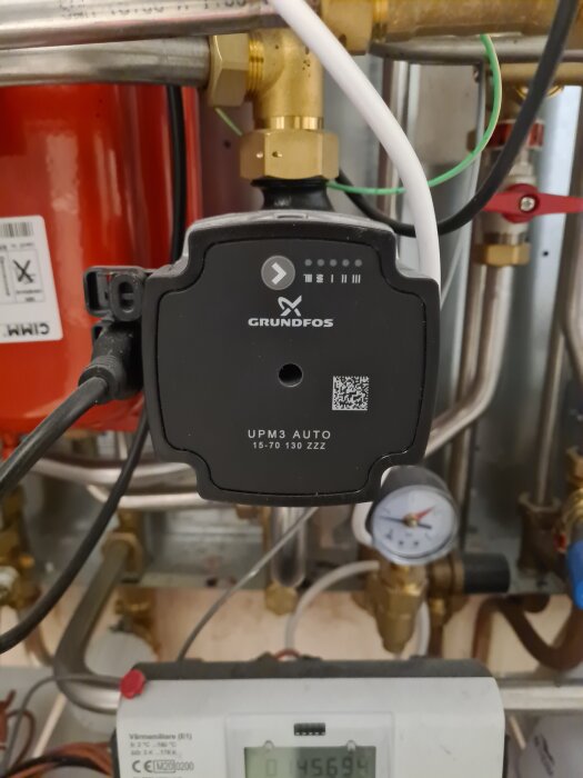 En Grundfos UPM3 AUTO-pump med avstängda dioder, omgiven av rör och en tryckmätare.