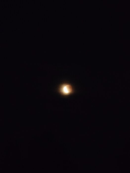 Suddig nattbild med en ljus prick mot mörk himmel.