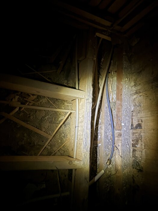 Rörinstallation i golvbjälklag med grått och blått rör som går rakt igenom utan synliga förgreningar eller anslutningar till badrum.