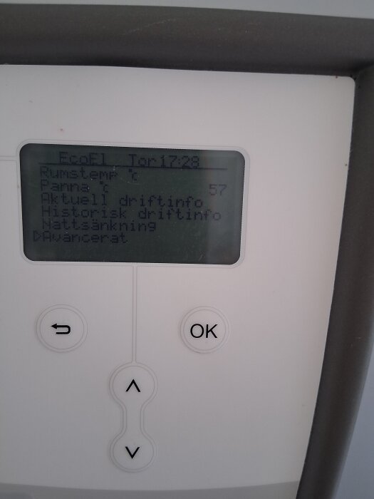 Pannans kontrollpanel med display som visar rumstemperatur och panna, samt knappar för att justera inställningar. Displayen visar olika driftinformation.