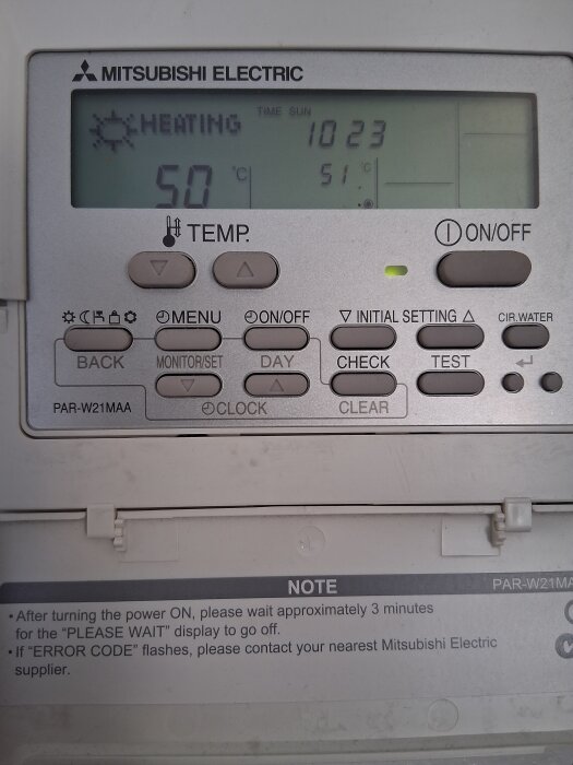 Display på Mitsubishi Electric värmepanna visar aktuell temperaturinställning som 50 °C samt tid och dag.