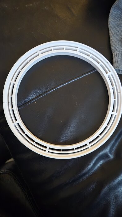 Vit plastdel på mörk yta, del av Purus 2014-golvbrunnssystem, diskuterad i samband med badrumsrenovering och korrekt montering.