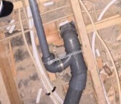 Röranslutning med flera böjar under ett handfat, inklusive en skarp 90-graderssväng, i ett byggprojekt.