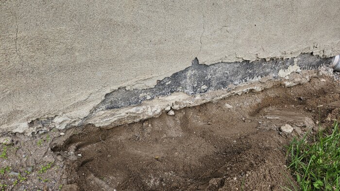 Sprucken husgrund med synlig mark och delvis avslagen puts, hus från 1968 med kallt golv.