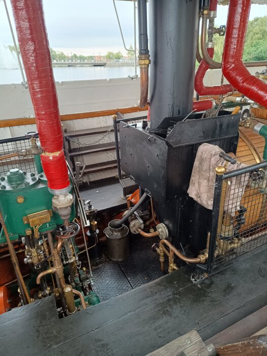 Interiör av ångmaskineri på ångslupen Gerda med rör och ventiler i fokus, sett vid kajen i Eskilstunaån.
