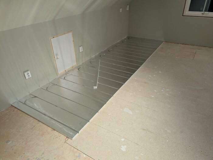 Golvvärmeinstallation med LK Combiboard 18 skivor i ett rum med synliga spår för slangar. Väggar och tak är målade i ljus färg.