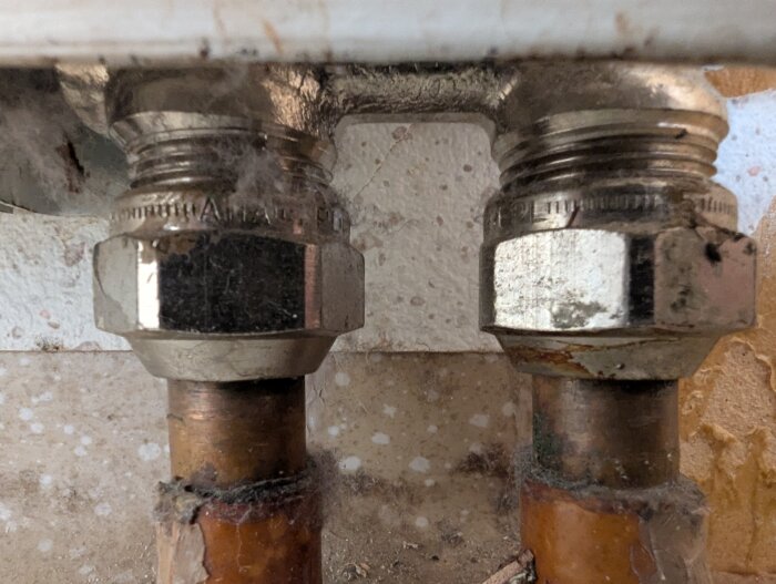 Närbild på elementanslutningen med två metallrör och stora muttrar, del av ett avstängt uppvärmningssystem.