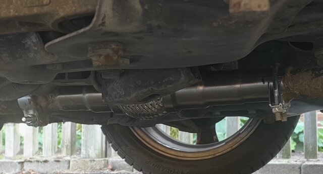 Undersidan av en bil med ett nyligen installerat flexrör, avgastätning och klammer.