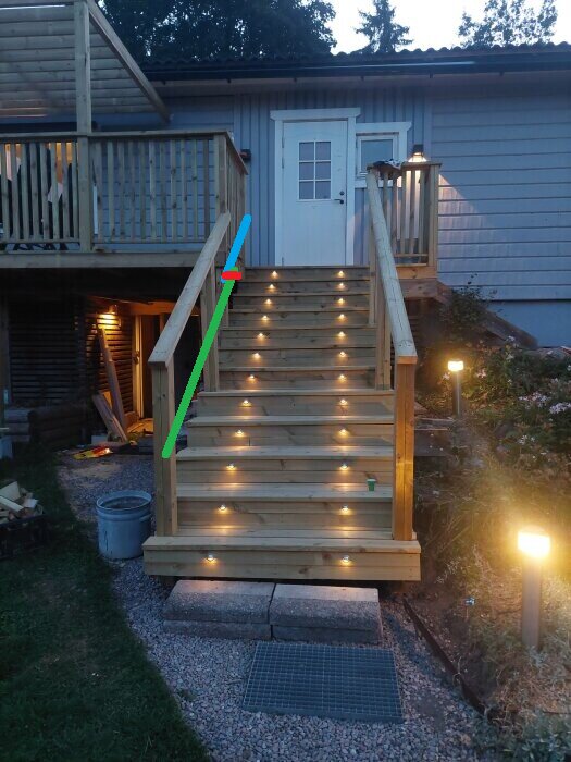 Belysning på trätrappa upp till altan vid hus, med räcken markerade i olika färger.
