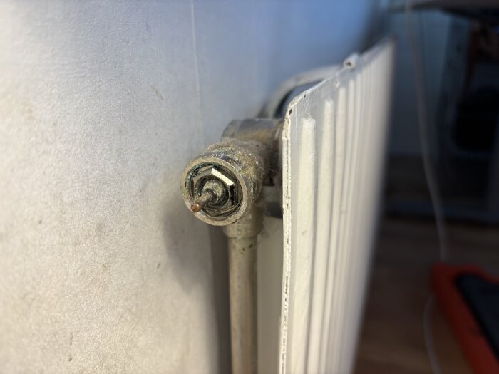 Radiator med AGA-ventil som behöver bytas ut, ventilen sitter svåråtkomligt på sidan av radiatorn.