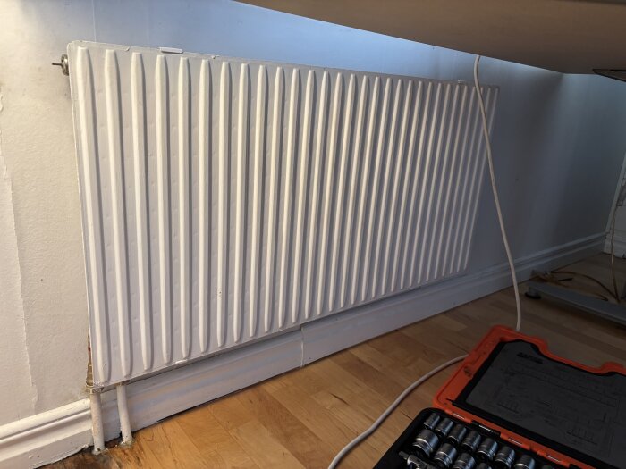 Värmeelement mot en vägg med en verktygslåda nedanför.