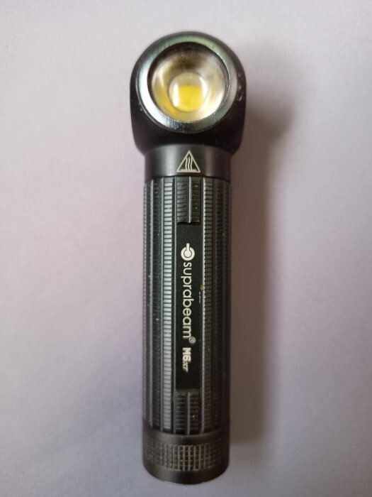 Svart Suprabeam-ficklampa med magnetfäste och hållare, laddningsbar via micro-usb, visas på en ljus bakgrund.