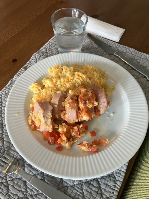 Tallrik med ugnsfalu, blomkålsris, morot samt ingefära- och vitlökspasta, med glas vatten bredvid.
