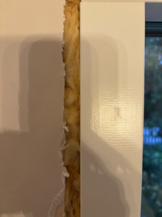 Gipsvägg och fönsterkarm med synlig isolering i springa, oisolerat område väntar på ångtät tejp före installation av inomhusfoder.