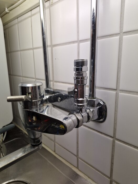 Vattenkran med teflontejp lindad runt ett rör för att förhindra läckage, monterad på en kaklad vägg.