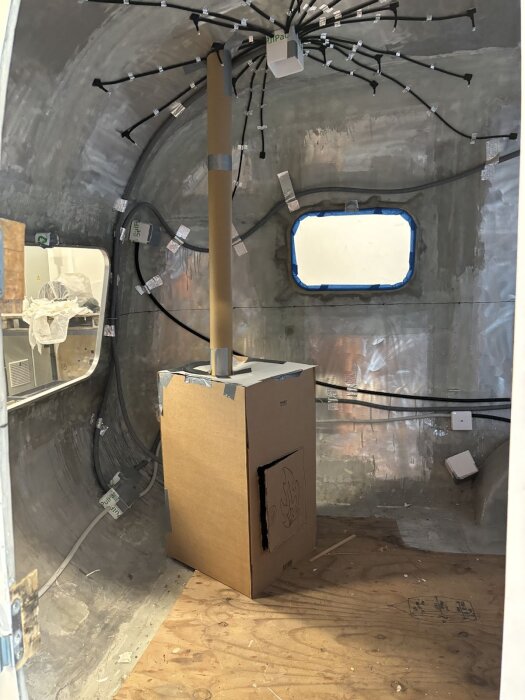 Modell av bastuaggregat i wellpapp avsedd för placering i en vagn, med en simulerad skorsten och kablar i taket.