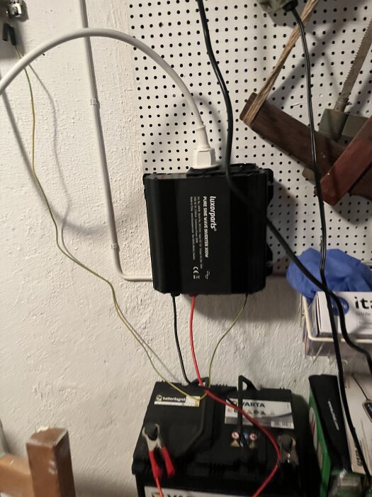 Inverter kopplad till ett fritidsbatteri på en vägg, med kablar anslutna för elförsörjning.