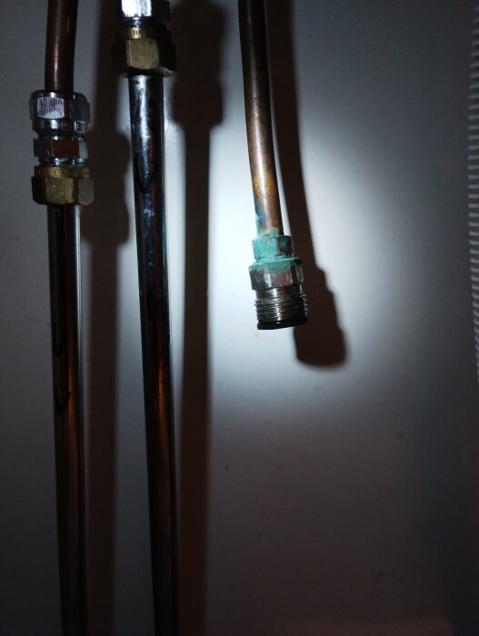 Ärgad vattenanslutning vid tvättmaskinsbyte, synlig kopparledning och koppling belagd med grönaktig ärg, spotlightbelysning.