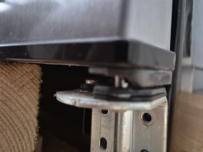 Kylskåpsdörr med modifierat gångjärn som visar metalldistans och justering för att åtgärda knakande ljud och självstängande effekt.