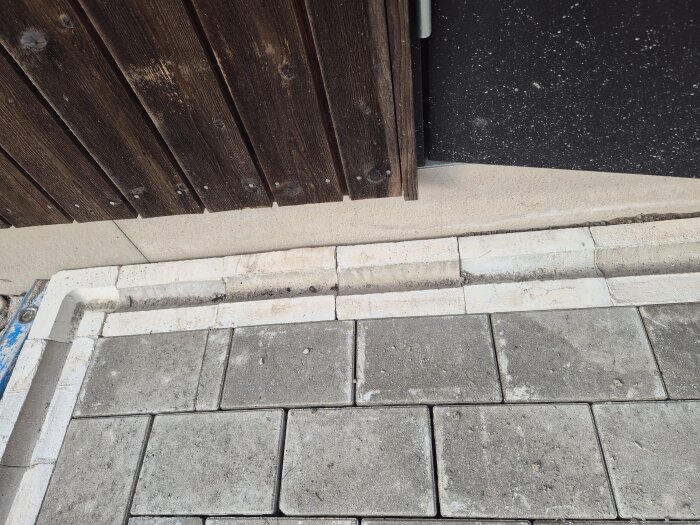 Glipa mellan husgrund och stenplattor, varierar från ingen till 4 cm. Träpanel på väggen, ojämnt installerade plattor.