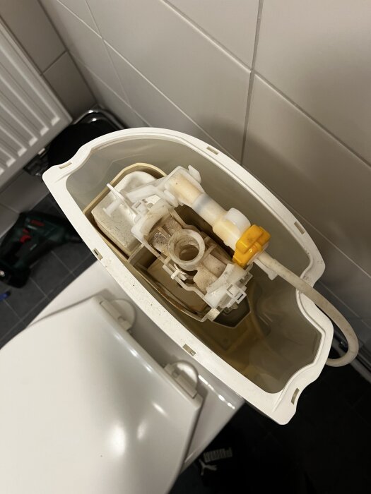 Öppen toalettcistern från en IFÖ toalett från 2015, visande inloppsventil och mekanismer.