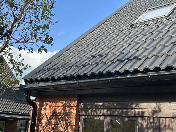 Tak med nylagda takpannor, hängränna och stuprör. Hängrännan verkar luta utåt från fasaden.