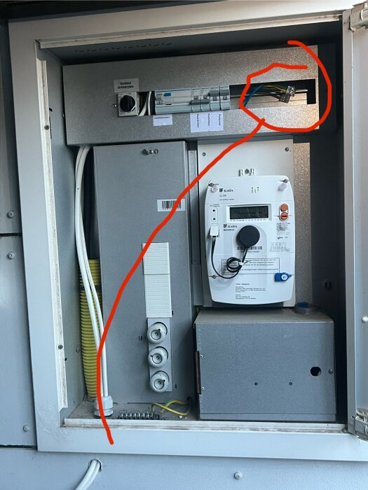 Elcentral öppnad, med markerad del i rött för potentiell installation av Zaptec Go 2, synliga kablar och mätare.
