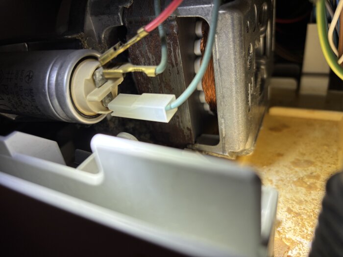 Diskmaskinens nedre del med kalkavlagringar och stillastående vatten under en motor och elkablar.