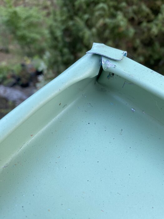 Grönt takmaterial med avslitet hörn, fotat utomhus.