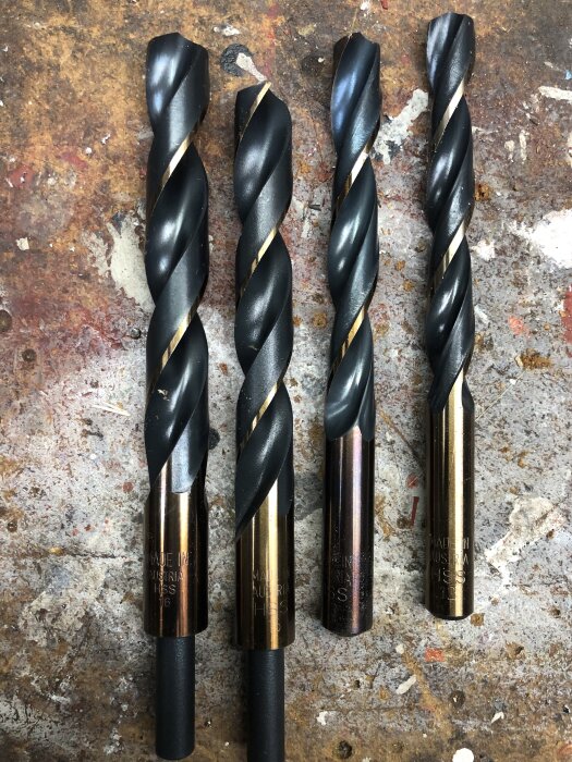 Fyra borr av metall ligger på en arbetsbänk, redo att testas för att borra hål i traktor.