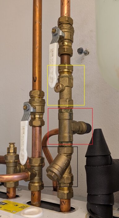 Rörkopplingar och ventiler för bergvärmepump med vit, svart, och gulmarkerade komponenter. Utrymme för att installera expansionskärl.