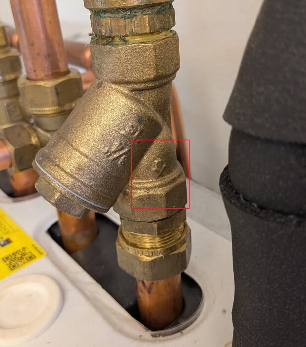 Rörkoppling med pilmarkering, troligen filter eller ventil för Daikin Altherma 3 Geo installation. Kopparrör anslutna till enhet.