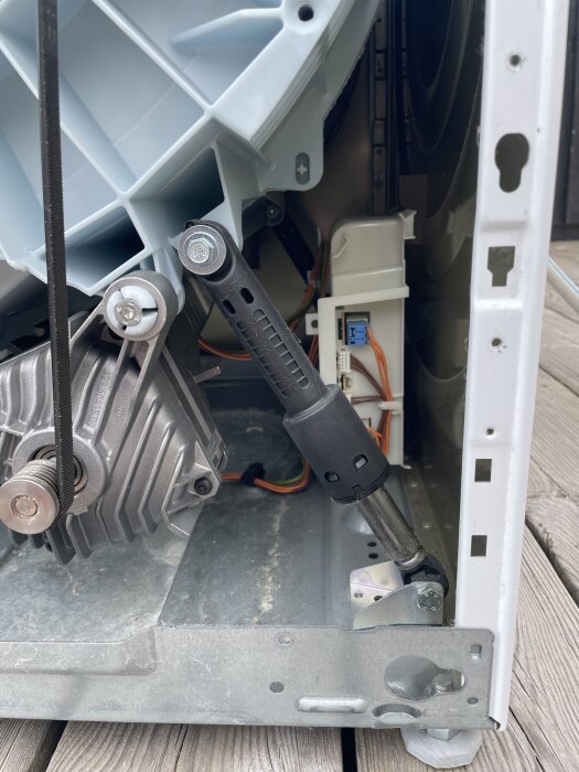 Insidan av en maskin med en remskiva, kompressionsdämpare och kablar, alla rengjorda och undersökta för skador.