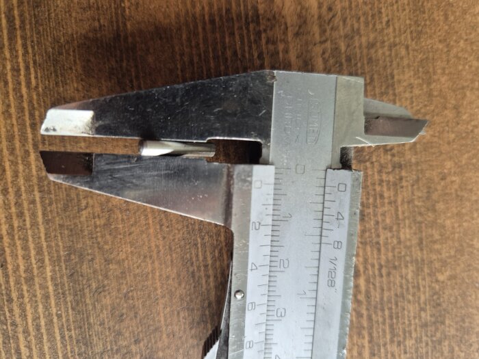 Skjutmått mäter en liten komponent, troligen ett hjul till terrassfönster. Måttet på komponenten verkar vara viktigt.