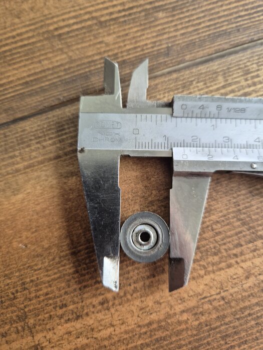 En skjutmått mäter diametern på ett litet, hjulformat objekt som används för terrassfönster.